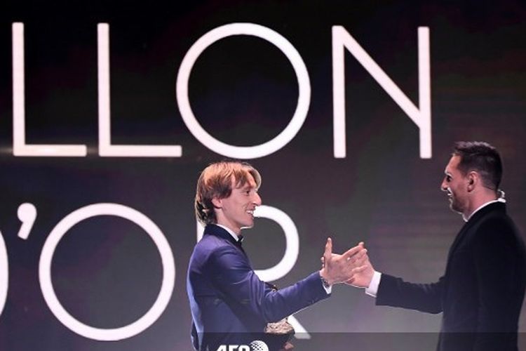 Pemain Real Madrid peraih Ballon dÓr 2018, Luka Modric, menyerahkan trofi pemain terbaik dunia itu kepada Lionel Messi yang memenanginya tahun ini.