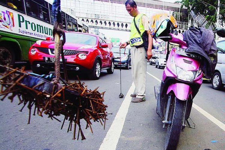 Anggota  relawan ranjau paku dari komunitas Sapu Bersih Ranjau Paku, Siswanto, mengambili paku yang bertebaran di Jalan Hasyim Ashari, Roxy, Jakarta, Senin (9/1), dengan alat buatan sendiri. Siang dan malam para relawan bergantian mengambili paku walaupun kadang harus berhadapan dengan risiko keselamatan, termasuk ancaman dari sindikat penebar paku.