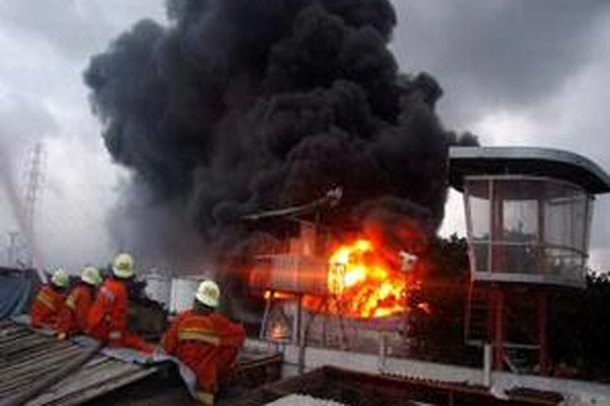 Petugas dari Dinas Pemadam Kebakaran DKI Jakarta, melakukan pembasahan di permukiman warga yang berada di dekat Depo Pertamina Plumpang, Jakarta Utara, yang terbakar hebat dan meledak, Minggu (18/1) malam hingga pada pagi hari. Depo 24 berkapasitas 5.000 kilo liter yang terbakar ini diperkirakan berisi sekitar 2.500 kilo liter bahan bakar minyak. 