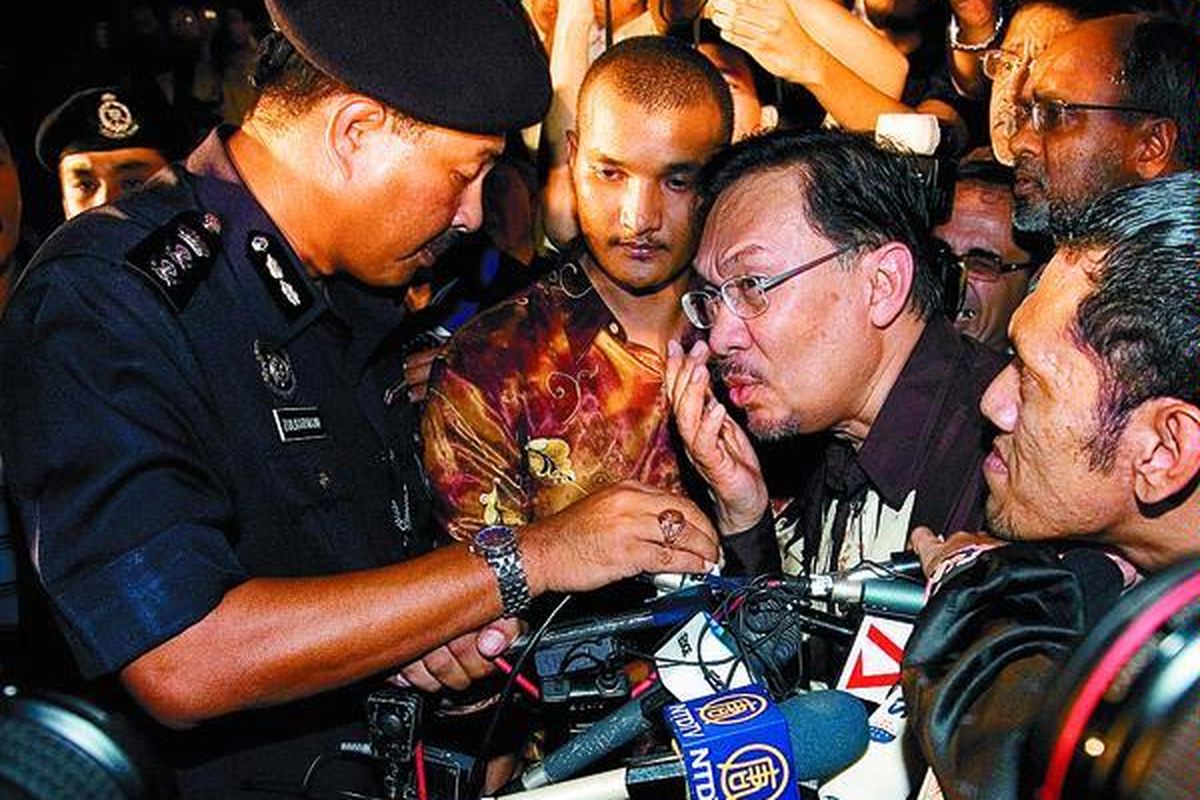 Mantan Wakil Perdana Menteri Malaysia Anwar Ibrahim (kedua dari kanan), Senin (14/4) di Kuala Lumpur, mendengarkan keterangan dari polisi. Seyogianya oposisi melakukan aksi damai dengan turun ke jalan pada malam hari untuk merayakan pencabutan larangan berpolitik praktis bagi Anwar. Namun, aksi damai itu bubar setelah sempat berlangsung selama satu jam.  