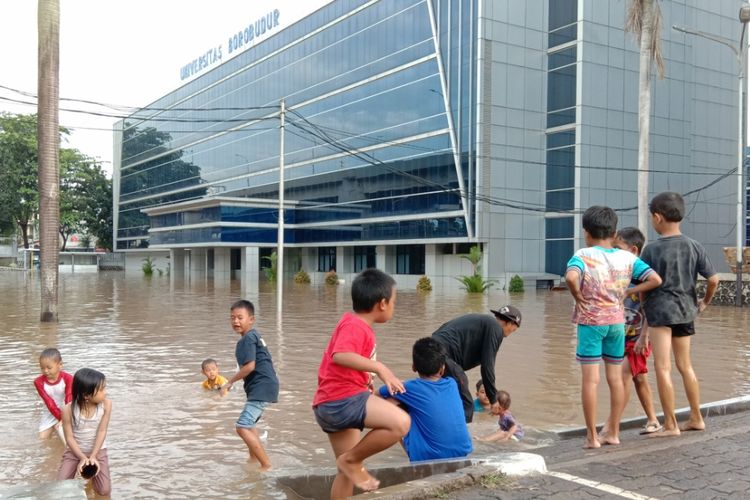 Beberapa anak di lapangan parkir Universitas Borobudur memanfaatkan genangan banjir sedalam lebih kurang 1 meter untuk berenang dan bermain air, Jakarta, Selasa (25/2/2020).