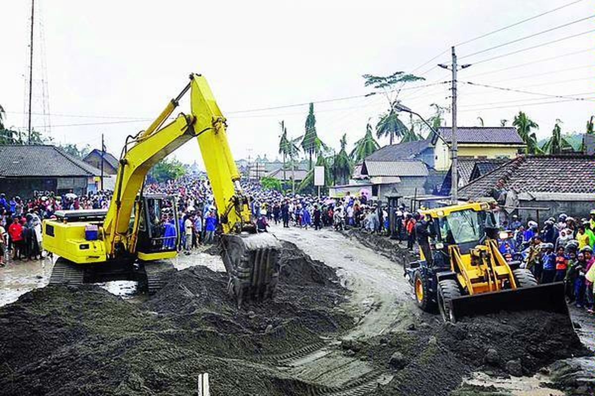 Alat berat dikerahkan untuk mengeruk pasir akibat banjir lahar dingin dari Kali Putih, yang meluap hingga Jalan Raya Yogyakarta-Muntilan di Desa Jumoyo, Salam, Magelang, Jawa Tengah, Minggu (5/12).