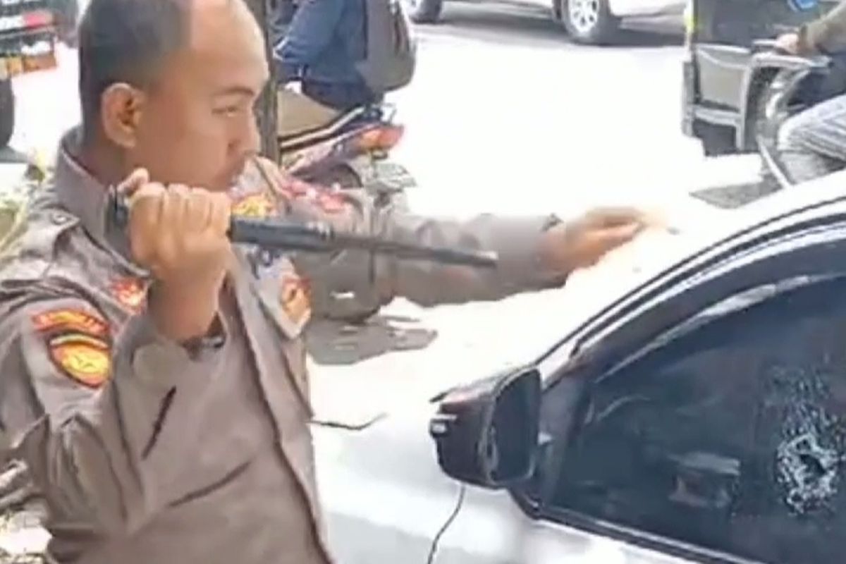 Aipda Donny Yanuar saat memecahkan kaca mobil untuk menolong balita yang terkunci, Selasa (2/4/2024) pagi.