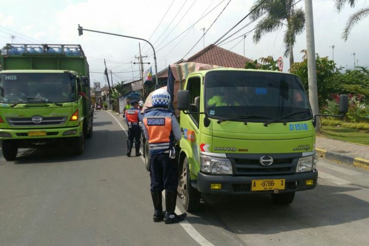 Seorang petugas sedang memeriksa kelengkapan surat kendaraan truk yang melintas di Jalan Raya Bogor - Sukabumi, Caringin, Bogor, Jawa Barat, Selasa (11/7/2017).