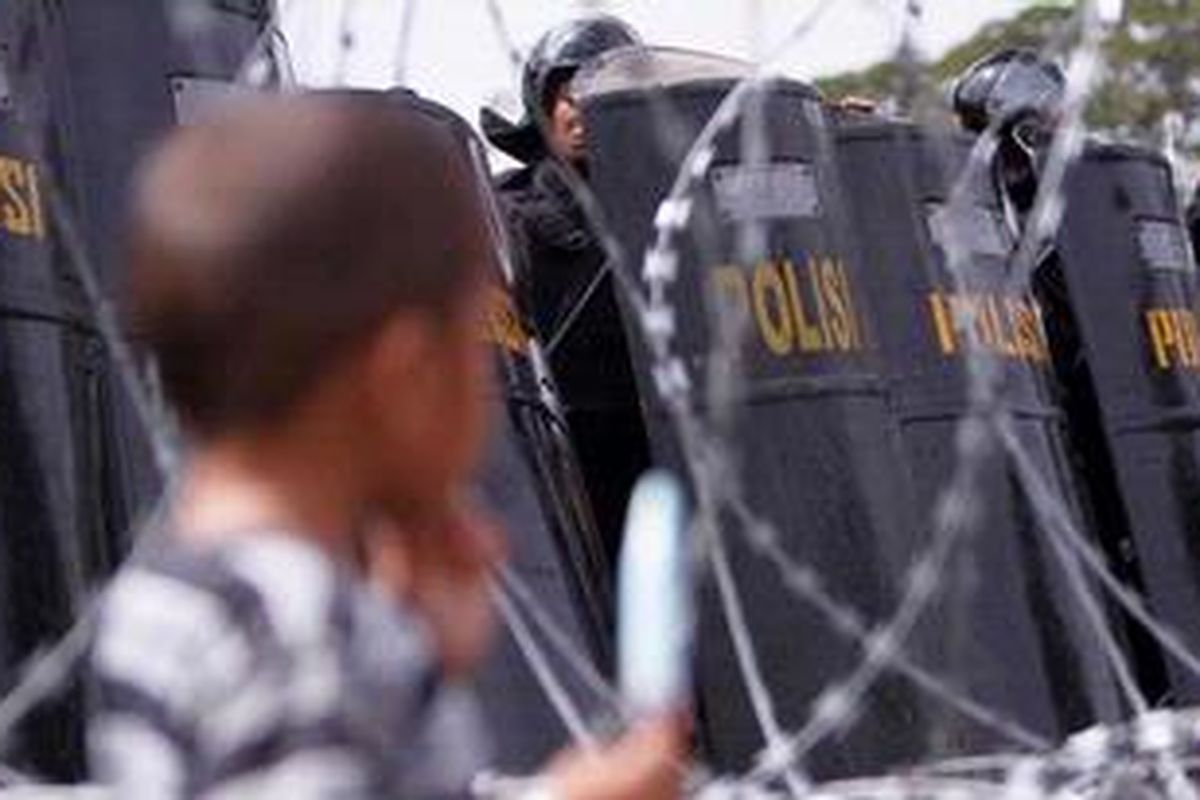 Anggota kepolisian berjaga saat ribuan buruh dari berbagai organisasi serikat pekerja menggelar aksi unjuk rasa dalam rangka memperingati Hari Buruh Sedunia (May Day), di depan Istana Negara, Jakarta, Minggu (1/5/2011). Ribuan buruh tersebut menuntut pemerintah untuk mengesahkan Rancangan Undang-Undang Badan Penyelenggara Jaminan Sosial dan penghapusan outsourcing. 