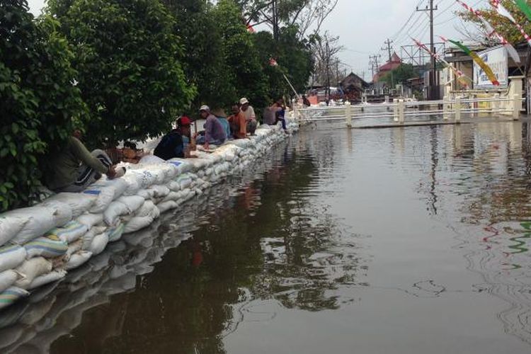 Aliran air rob di menggenangi Kali Sringin dibendung menggunakan tanggul sementara di depan Mapolsek Genuk, Semarang.