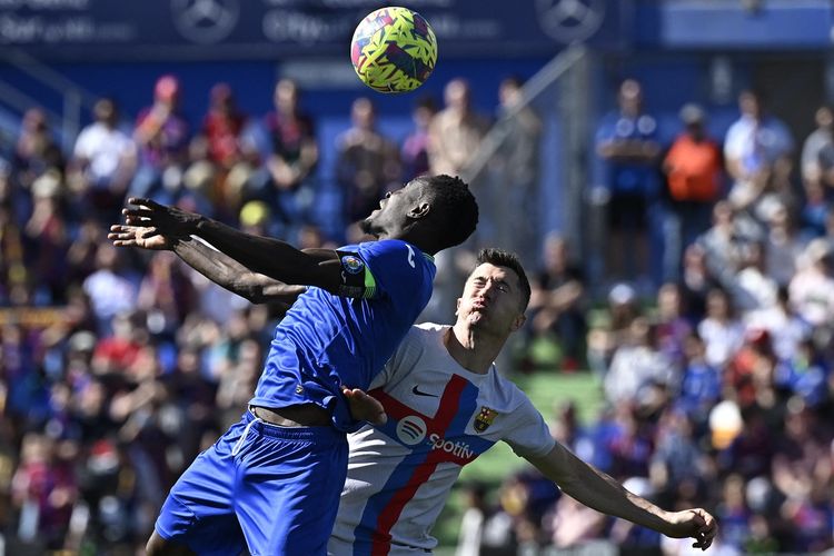 Bek Getafe Djene Dakonam (kiri) berduel dengan penyerang Barcelona Robert Lewandowski dalam laga lanjutan Liga Spanyol musim 2022-2023. Laga Getafe vs Barcelona berlangsung di Coliseum Alfonso Pérez pada Minggu (16/4/2023) malam WIB.