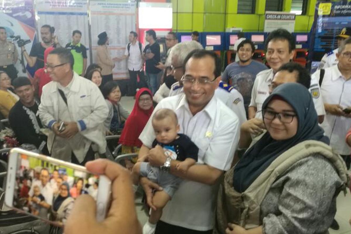 Menteri Perhubungan Budi Karya Sumadi menggendong bayi dari calon penumpang kereta api di Stasiun Gambir, Jakarta, Jumat (14/4/2017)