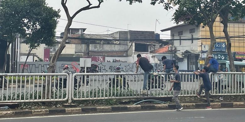 Sejumlah pejalan kaki yang melompati pagar di median jalan depan mal Kota Kasablanka, Jakarta Selatan. Adanya pagar di median jalan membuat perjalanan pejalan kaki menjadi tidak efisien. Tanpa melompati pagar, pejalan kaki harus menempuh jarak hampir 800 meter dan naik turun 40 anak tangga JPO untuk menjangkau lokasi yang sebenarnya hanya berjarak kurang dari 50 meter dari titik awal.