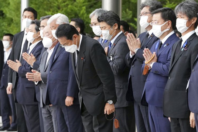 Japan's Prime Minister Fumio Kishida, center, officials and employees offer prayers towards a hearse which carries the body of former Prime Minister Shinzo Abe, which makes a brief visit to the Prime Minister's Office Tuesday, July 12, 2022, in Tokyo. (AP Photo/Eugene Hoshiko, Pool)
