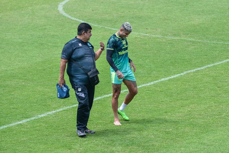 Penyerang Persib Bandung Ciro Alves hendak meninggalkan lapangan latihan di Stadion Persib, Sidolig, Bandung ditemani dokter tim Rafi Ghani yang memeriksannya. Ciro tampak kesakitan usai berbenturan di game latihan.