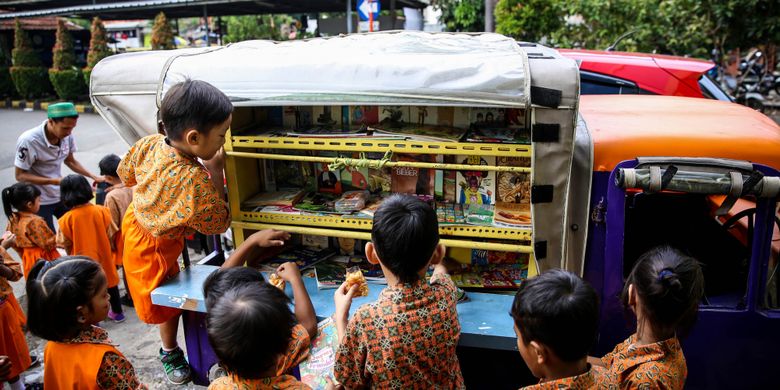 Anak-anak sekolah Paud saat membaca buku di bemo perpustakaan saat jam istirahat di Rusun Karet Tengsin, Jakarta, Jumat (7/12/2018). Pak Sutino (58) adalah sopir bemo yang merintis bemo tuanya menjadi perpustakaan keliling bagi anak-anak sejak tahun 2013.