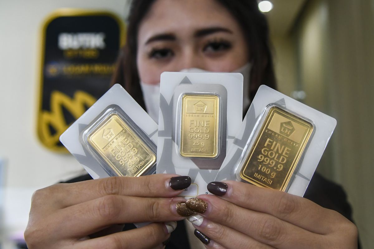 Karyawan menunjukan emas batangan di Butik Emas Antam, Kebon Sirih, Jakarta, Senin (18/1/2021).