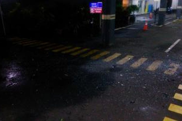 Serpihan kaca dari Wisma Kosgoro jatuh dan berserakan di lahan parkir Oil Centre Building, gedung di samping Wisma Kosgoro, Senin (9/3/2015).