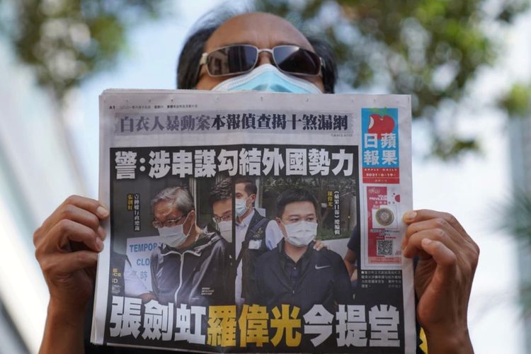 Seorang pendukung pro-demokrasi menunjukkan koran Apple Daily saat persidangan dua eksekutif koran pro-demokrasi atas tuduhan pelanggaran Undang-Undang Keamanan Nasional, di Hong Kong, China, 19 Juni 2021.