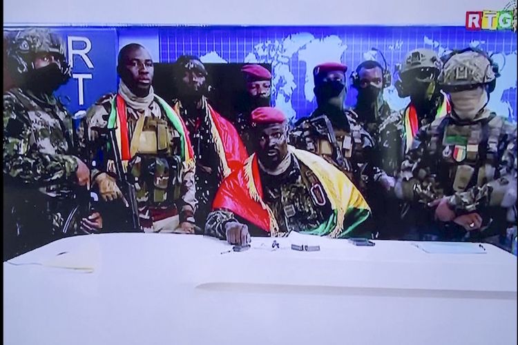 Tangkapan layar dari video menunjukkan pemimpin kudeta Guinea, Letnan Kolonel Mamady Doumbouya (tengah) dikelilingi pasukannya dan berbalut bendera negara, berbicara dalam pidato untuk bangsa di ibu kota Conakry, Minggu (5/9/2021). Junta militer Guinea menahan Presiden Alpha Conde setelah terjadi baku tembak sengit selama berjam-jam.