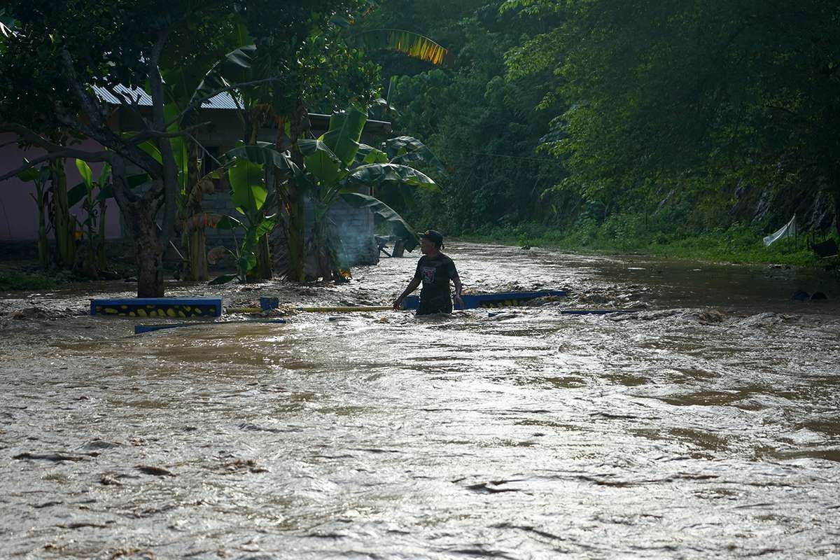 Seorang warga melintasi arus deras banjir di Desa Alale, Kabupaten Bone Bolango, Gorontalo, Kamis (11/6/2020). Hujan yang melanda daerah itu sejak hari Rabu (11/6) malam, menyebabkan meluapnya sungai Bone dan bendungan jebol sehingga merendam ratusan rumah warga.