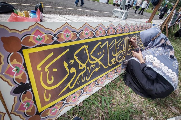 Seorang santriwati tengah melukis kaligrafi memecahkan rekor di Jalan Komplek Perkantoran Pemkab Bandung Barat, Kamis (10/11/2022).