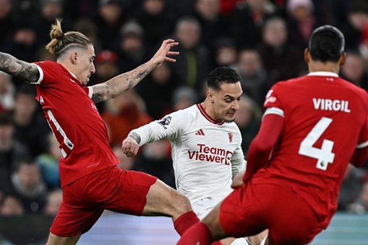 Bek Liverpool, Konstantinos Tsimikas (kiri) dan Virgil van Dijk, coba menahan upaya pemain sayap Manchester United, Antony. Laga Liverpool vs Man United pada pekan ke-17 Liga Inggris 2023-2024 tersebut digelar di Stadion Anfield pada Minggu (17/12/2023). (Foto oleh PAUL ELLIS/AFP)