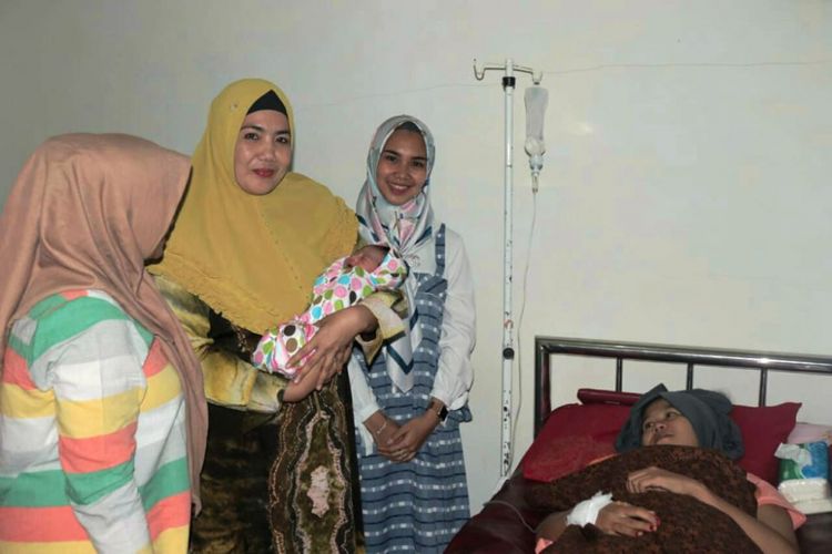 Pengurus Bhayangkari Polres Aceh Utara menggendong putra almarhum Bripka Anumerta Faisal,  yang lahir di Klinik Asyifa, Kecamatan Meurah Dua, Kabupaten Pidie Jaya Selasa (28/8/2018) 