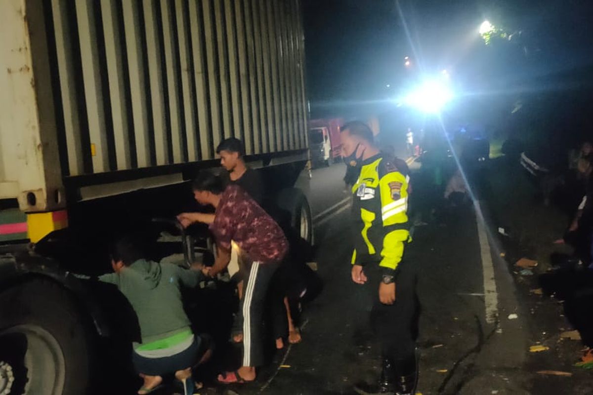 Petugas mengevakuasi korban kecelakaan yang melibatkan dua truk dan satu motor.