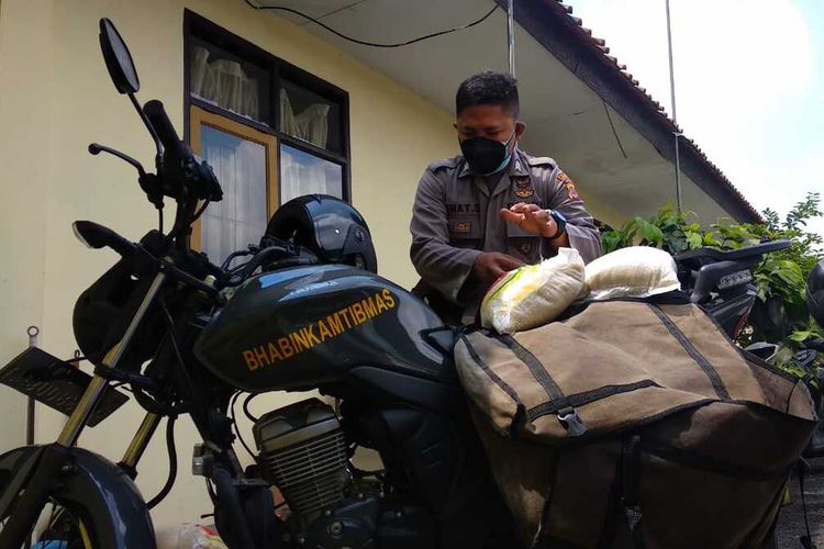 Petugas Bhabinkamtibmas Polsek Mangkubumi Polresta Tasikmalaya, mengantarkan beras bantuan ke warganya secara door to door memakai motor dinas yang dimodifikasi pakai keranjang, Selasa (24/8/2021).