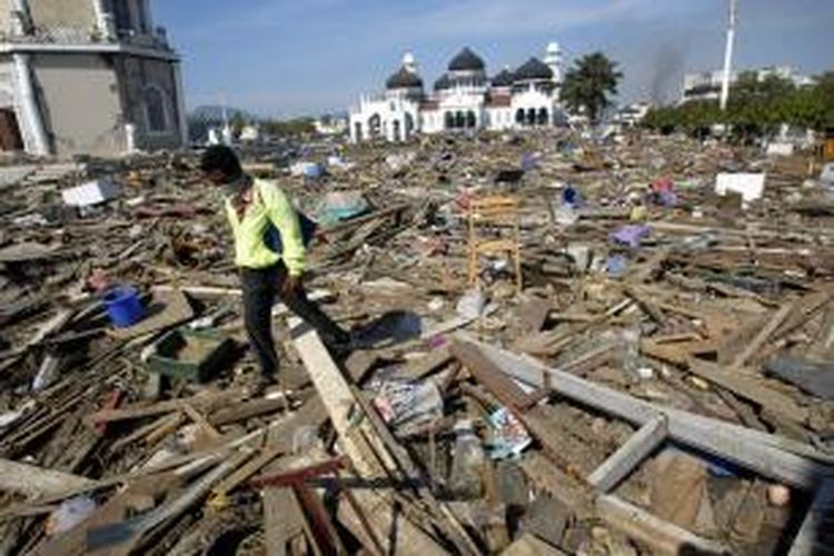 Seorang lelaki melintasi reruntuhan yang terempas tsunami dari Samudera Hindia hingga ke depan Masjid Raya di Banda Aceh, Nanggroe Aceh Darussalam. Gambar diambil pada 29 Desember 2004.