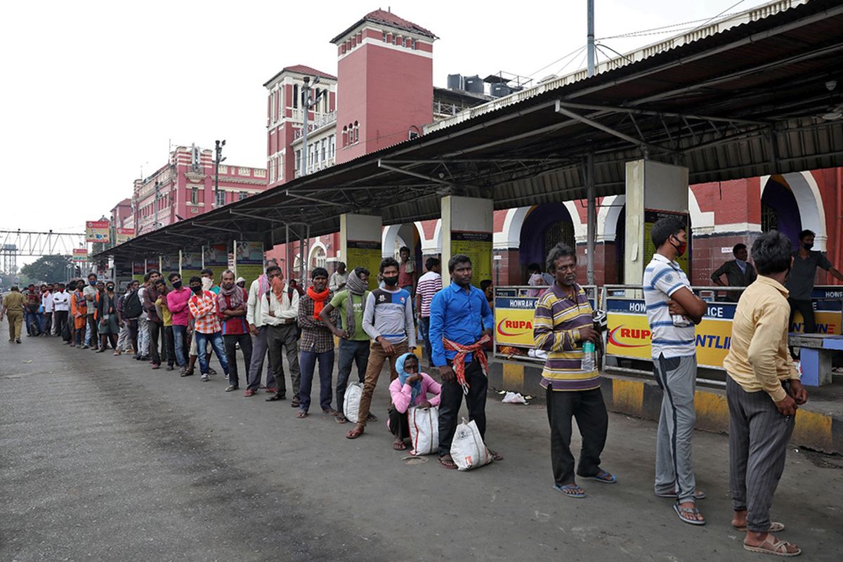 Para pekerja migran menunggu dalam antrean untuk menerima makanan gratis di luar stasiun kereta Howrah setelah Pemerintah India memerintahkan lockdown nasional untuk membatasi penyebaran penyakit virus corona (COVID-19), di Kolkata, India, Rabu (25/3/2020).