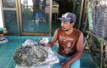 Surachet Chanchu, pemulung pantai sedang memegang bongkahan ambergis di rumahnya di Thailand.