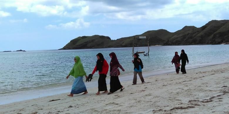 Beberapa wisatawan berjalan di Pantai Tanjung Aan, Lombok Tengah, Nusa Tenggara Barat.