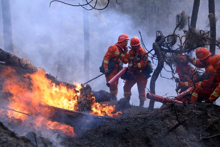 Pemadam kebakaran berusaha menjinakkan kebakaran hutan yang berkobar di Prefektur Liangshan, Xichang, Provinsi Sichuan, China, pada 31 Maret 2020. Sebanyak 19 orang tewas karena terperangkap tatkala berjibaku memadamkan api.