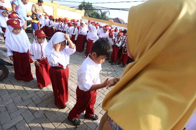 Guru bersalaman dengan murid baru kelas 1 saat hari pertama masuk sekolah, di SD Negeri Lengkong Wetan 1, Serpong Utara, Tangerang Selatan, Senin (16/7/2018). Sebanyak 120 murid baru di SDN Lengkong Wetan 1 nampak diantar oleh orangtua pada hari pertama tahun ajaran baru 2018/2019