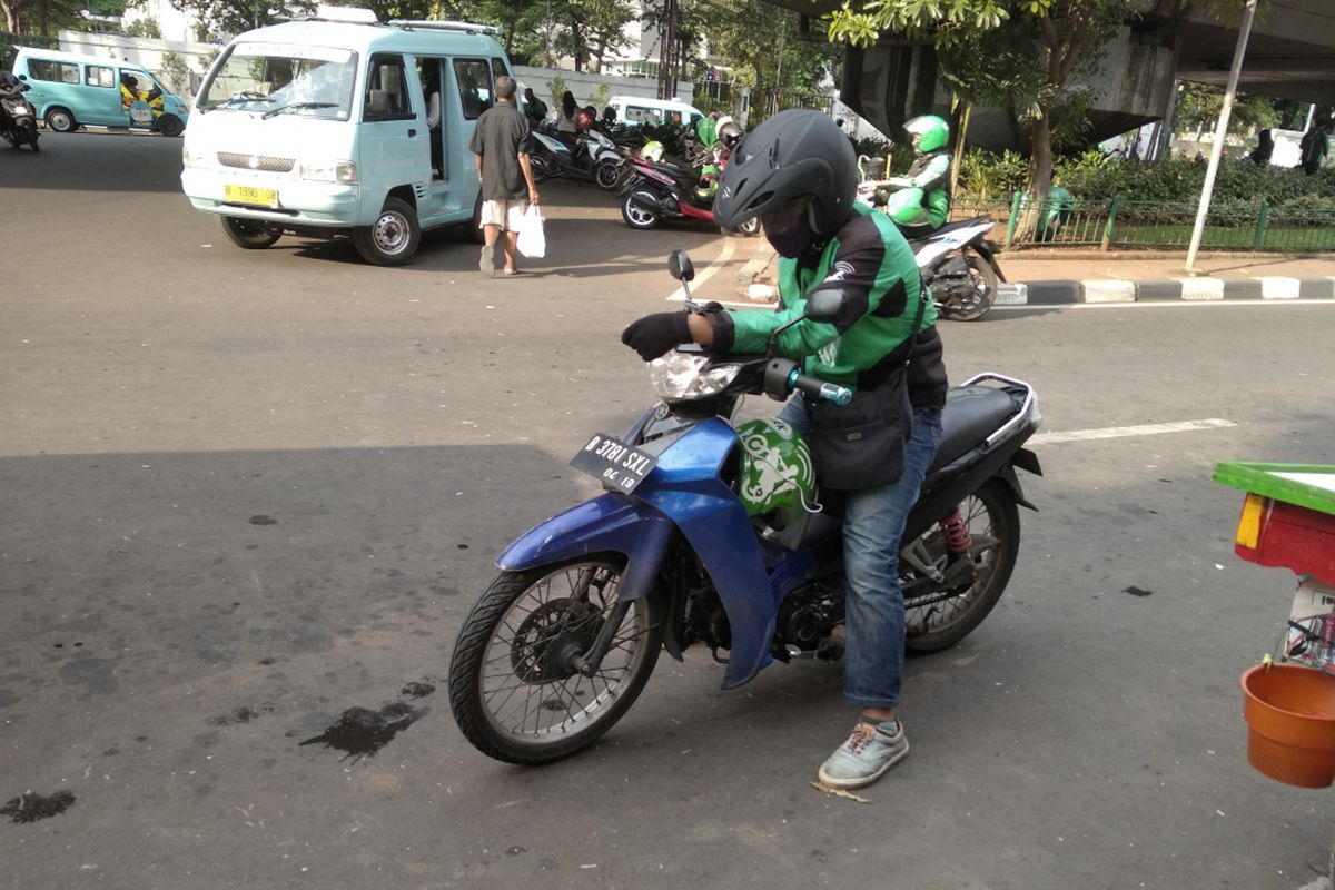 Pengendara Go-Jek yang sedang melihat notifikasi pesanan di kawasan Kalibata, Jakarta Selatan, Senin (2/4/2018)