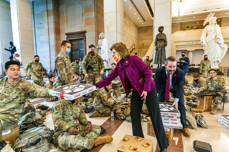 Anggota DPR Partai Republik Vicky Hartzler dan Michael Waltz, R-Fla memberikan pizza untuk anggota Garda Nasional yang siaga di Capitol Visitor Center, Rabu, 13 Januari 2021, di Washington. 