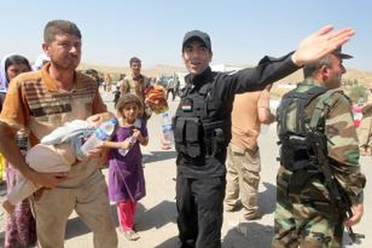 Pasukan Peshmerga membantu warga Yazidi memasuki wilayah aman setelah dikejar-kejar pasukan Negara Islam Irak dan Suriah (ISIS).