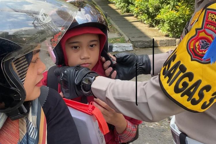 Anggota Satlantas Polrestabes Bandung saat bagikan helm kepada anak kecil dalam kegiatan Operasi Patuh Lodaya 2024 di simpang Jalan Pasteur - H.O.S Cokroaminoto, Kota Bandung, Jawa Barat, Selasa (16/7/2024)