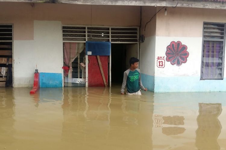 Seorang warga keluar dari rumahnya yang dilanda banjir di Perumahan Witayu, Kelurahan Sri Meranti, Kecamatan Rumbai, Pekanbaru, Riau, untuk mengungsi ke tenda pengungsian, Jumat (23/11/2018). 