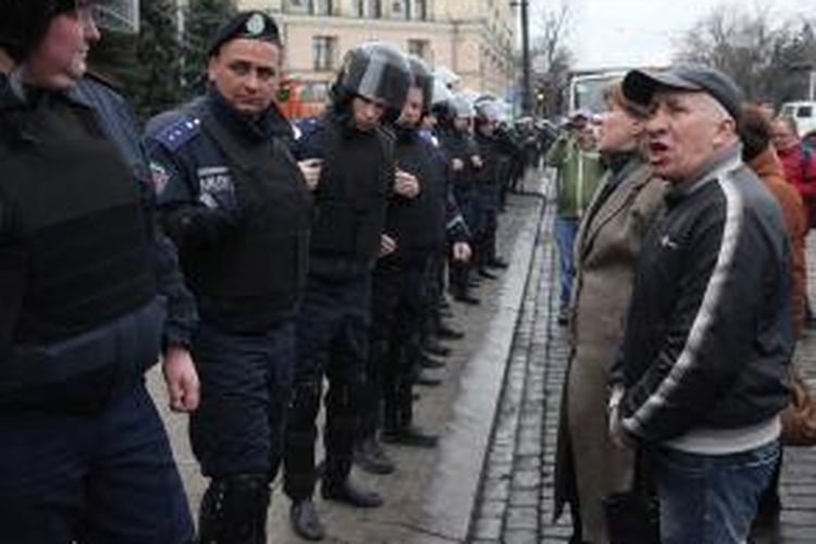 Polisi Ukraina berhadapan dengan para pengunjuk rasa di depan sebuah gedung pemerintahan di kota Kharkiv, wilayah timur Ukraina.