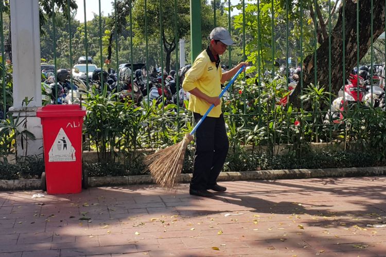 Ali Santoso (48) membersihkan sampah-sampah yang mengotori pedestrian di luar kawasan Monumen Nasional (Monas) di Jalan Medan Merdeka Selatan, Jakarta Pusat, Rabu (28/6/2017). Ia tidak libur pada hari Lebaran 2017.