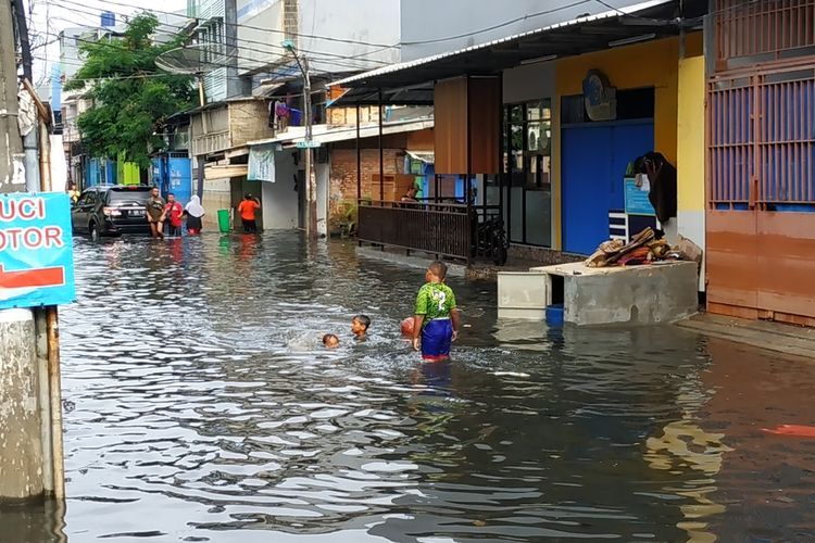Bocah-bocah tampak girang bermain air banjir yang penuh sampah di kawasan Jalan Teluk Gong, Penjaringan, Jakarta Utara, Sabtu (4/1/2020).