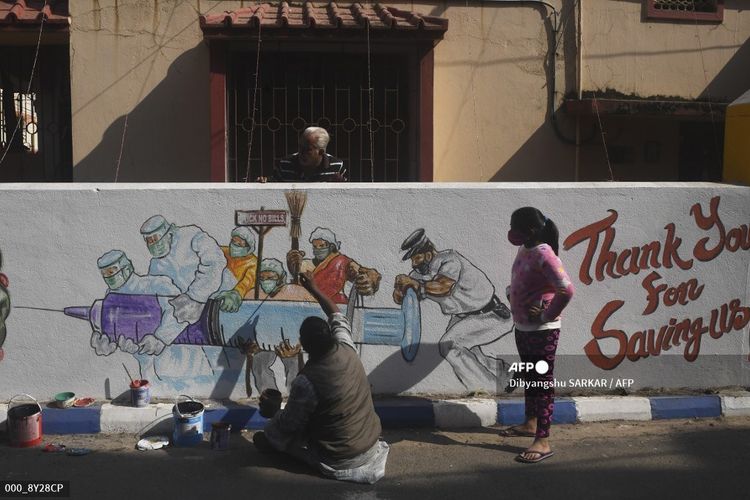 Seorang seniman memberikan sentuhan akhir pada mural yang menggambarkan pekerja garis depan membawa vaksin Covid-19 virus corona di Kolkata pada 2 Januari 2021.