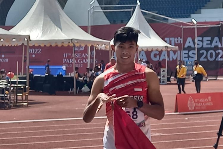 Atlet para-atletik Indonesia Sapto Yogo Purnomo berpose dengan bendara Merah Putih selepas memenangi laga final nomor lari 100 meter T37 putra ASEAN Para Games 2022 di Stadion Manahan, Solo, Senin (1/8/2022) siang WIB.