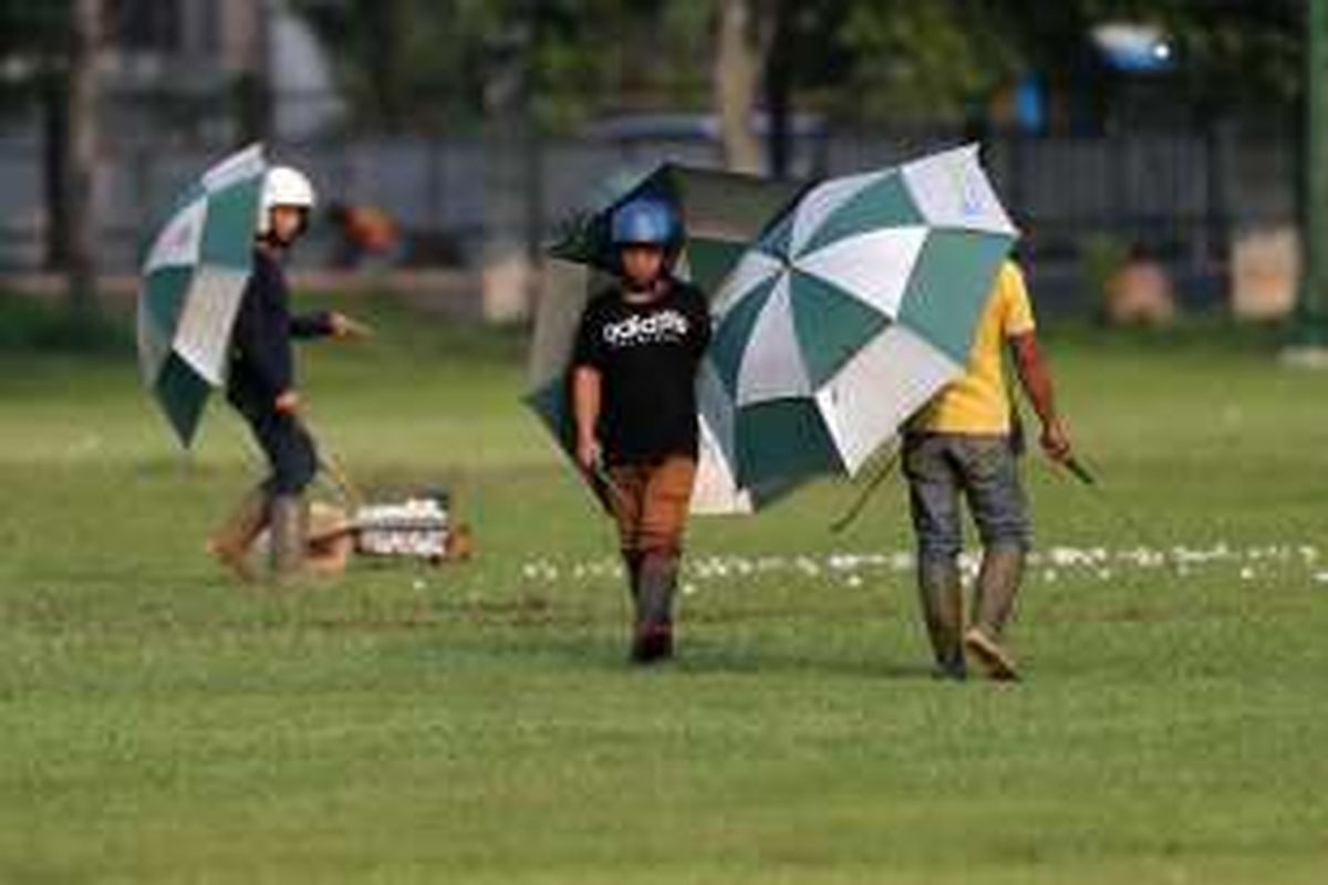 Beberapa pekerja mengumpulkan bola golf di Senayan Golf Driving Range, Jakarta, Rabu (16/7/2014). Demi keselamatan saat bekerja, mereka menggunakan helm dan payung agar terhindar dari pukulan bola. KOMPAS/TOTOK WIJAYANTO