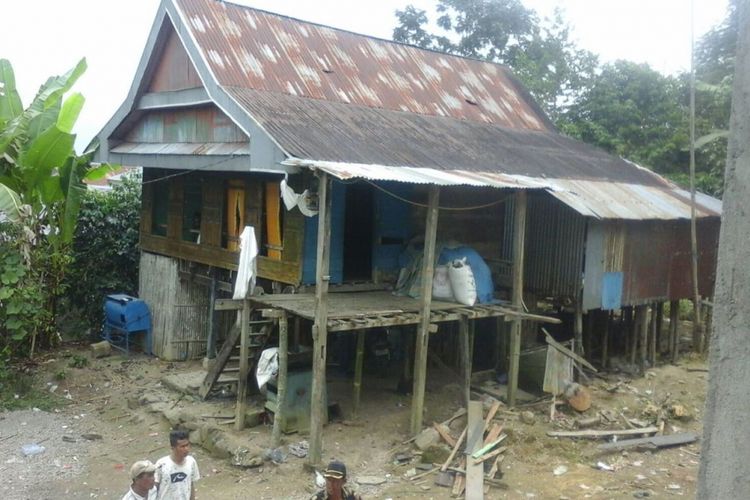 SA (40) tengah bersembunyi di atas bubungan rumahnya yang dikepung polisi usai membacok mertua dan anaknya, Jumat (18/8/2017).