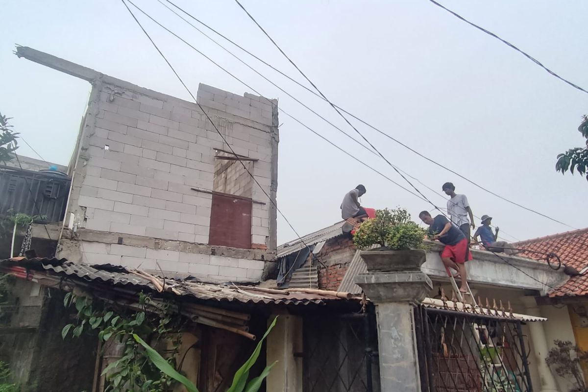 Warga gotong royong membersihkan puing-puing genting yang rusak akibat tertimpa hebel rumah Ana (56) saat atapnya terbang akibat angin kencang di Jalan Cimerak Tengah, Duren Sawit, Jakarta Timur, Selasa (26/12/2023).
