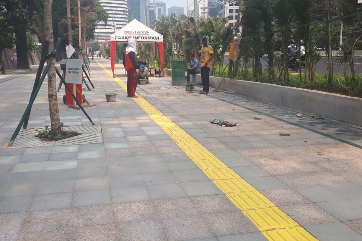 Para pekerja tampak membersihkan ubin di Trotoar sepanjang Jalan Sudirman - Thamrin, Selasa (31/7/2018)