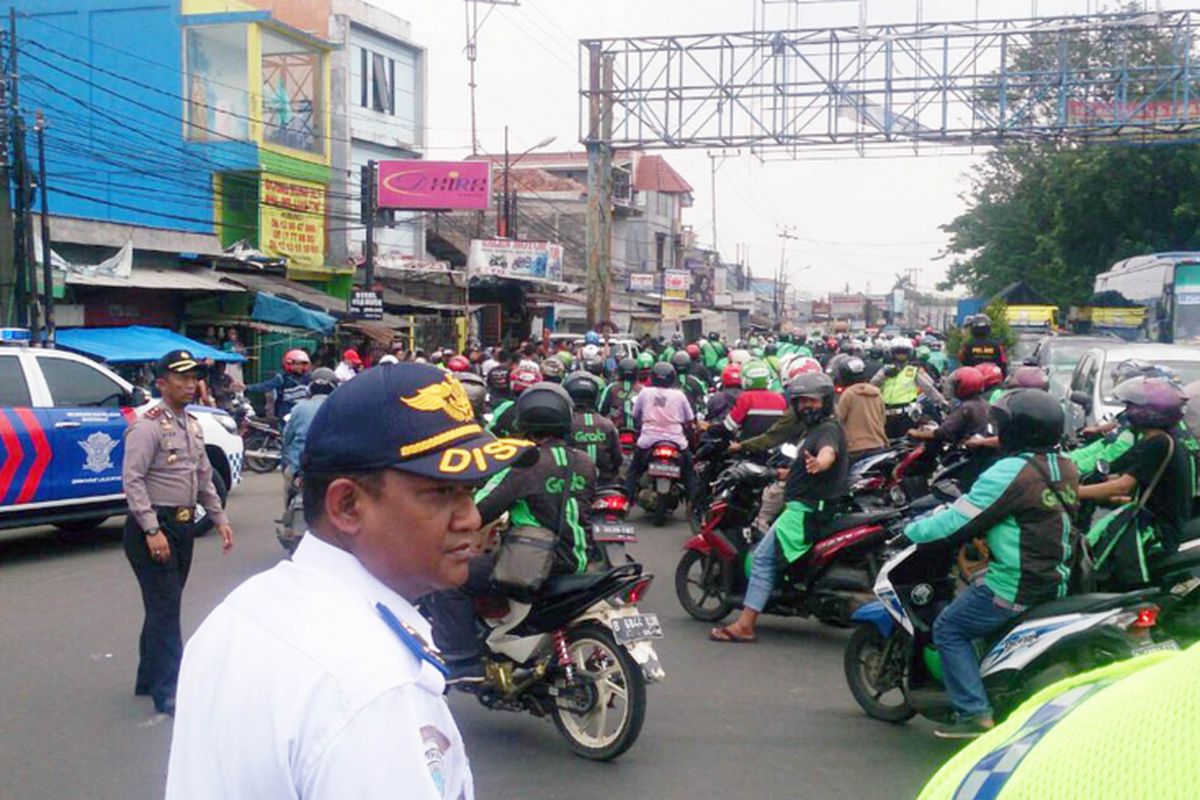 Puluhan pengemudi ojek online dari arah Depok melintasi Jembatan Fly Over Cibinong dan mendapat pengawalan dari aparat kepolisian setempat, Selasa (21/3/2017).