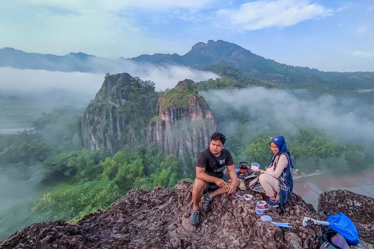 Pengunjung berfoto di Gunung Sepikul dengan latar belakang keindahan panorama alam.