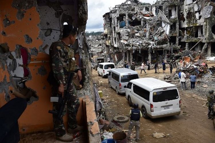 Militer terlihat tengah melihat kedatangan para jurnalis saat tiba di kota Marawi yang hancur setelah ISIS. (AFP/Ted Aljibe)