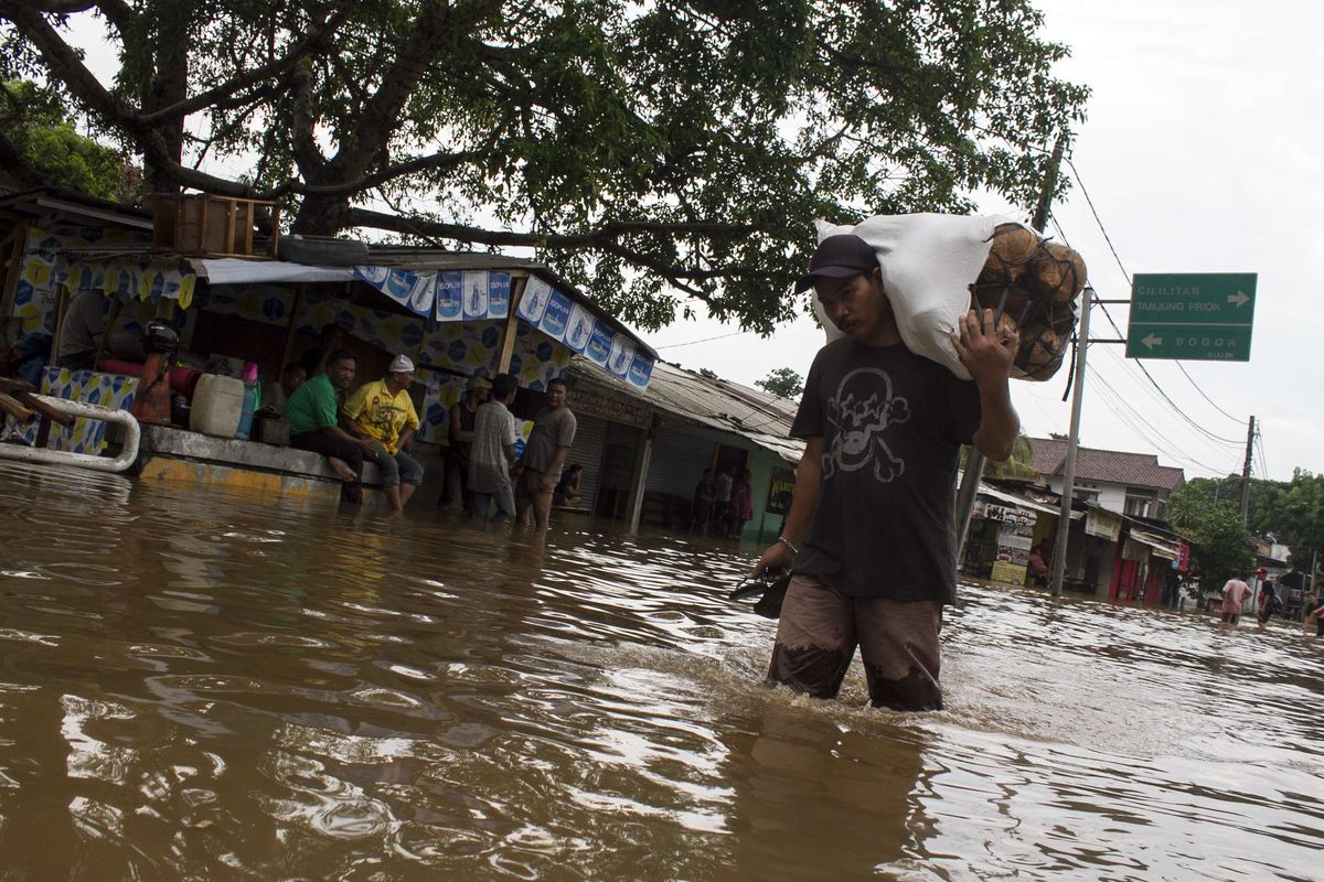 Sejumlah warga mengevakuasi barang berharga yang terendam banjir di Jl. Raya Pondok Gede, Kramat Jati, Jakarta Timur, Rabu (1/1/2020). Luapan air Kali Baru sebabkan wilayah Kramat Jati terendam hingga sebahu orang dewasa.